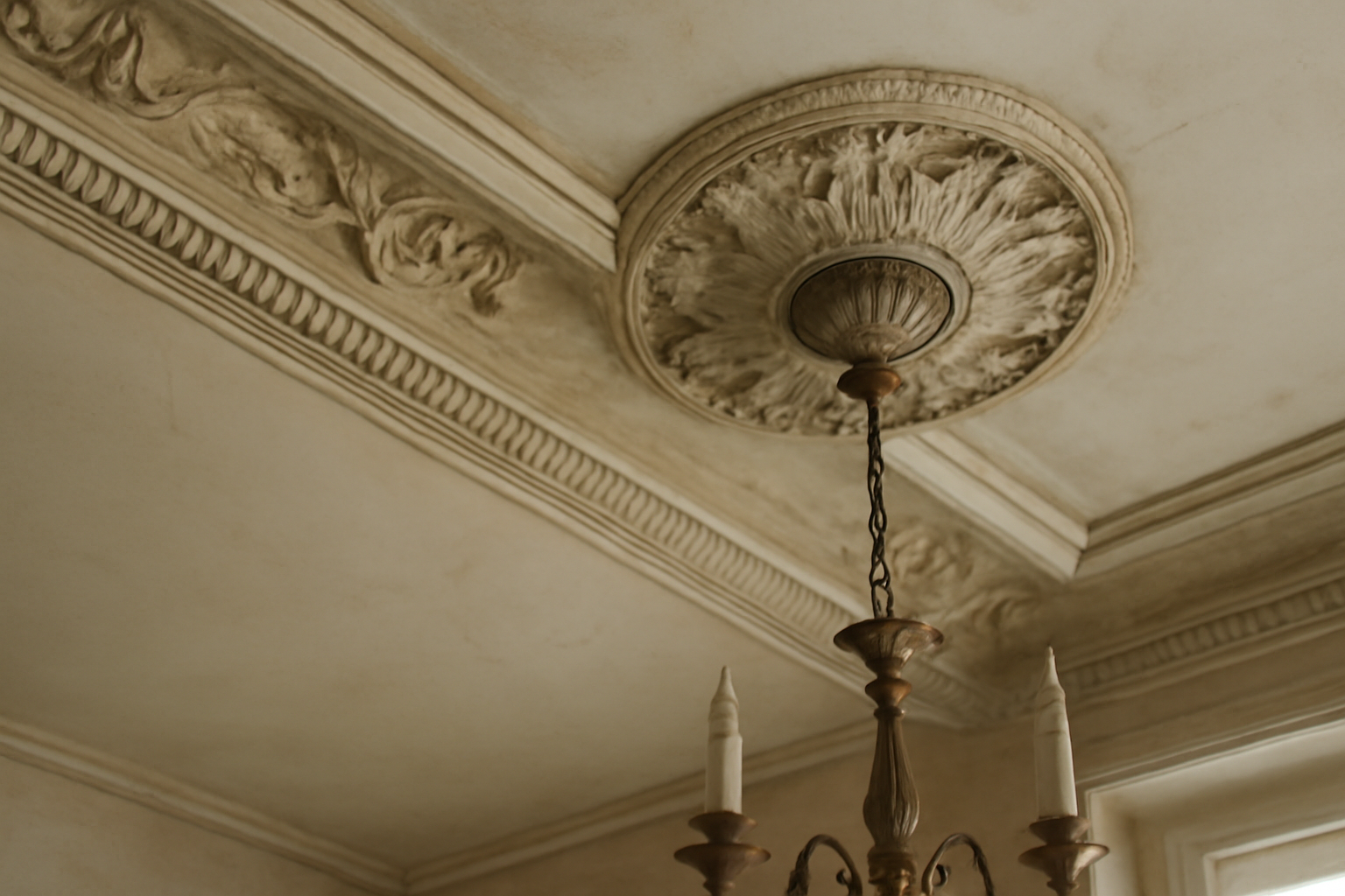Détail de plafond décoratif avec moulures, rosace et éclairage encastré — finition haut de gamme pour décoration intérieure